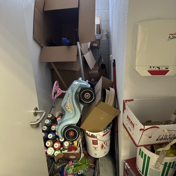 Unordentlicher Toilettenraum mit vielen Kartons, Farbeimern und Spielsachen